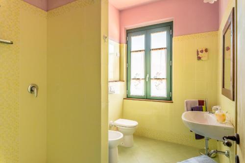 a bathroom with a sink and a toilet and a window at Alba al Rifugio Arcobaleno in Popiglio