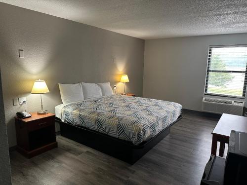 ein Schlafzimmer mit einem Bett, zwei Lampen und einem Fenster in der Unterkunft Motel 6 - Franklin, OH in Franklin