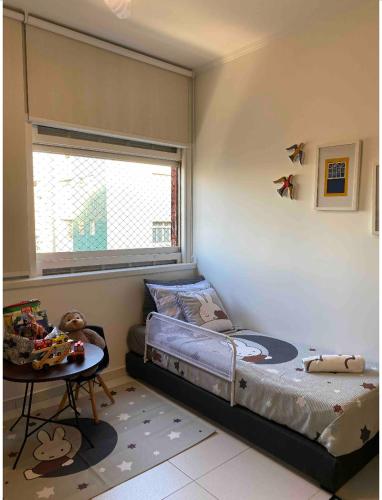 a bedroom with a bed and a table and a window at Studio Gonzaga 1 Quadra da Praia in Santos