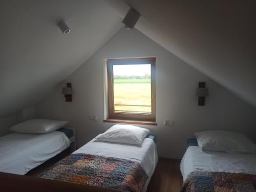 a attic room with two beds and a window at Piękne Zielone in Zator