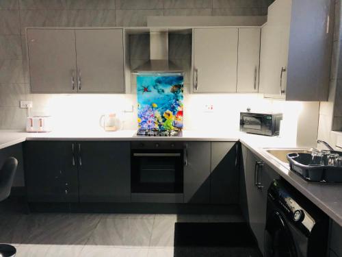 a kitchen with a sink and a stove top oven at Modern Travis House in Burnley