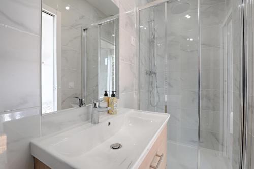 uma casa de banho branca com um lavatório e um chuveiro em White & Wood - Charmant appartement pour 4 em Vitry-sur-Seine