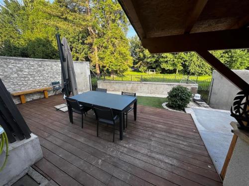 une table et des chaises noires sur une terrasse en bois dans l'établissement Maison terrasse au bord de l'eau, à Ébreuil