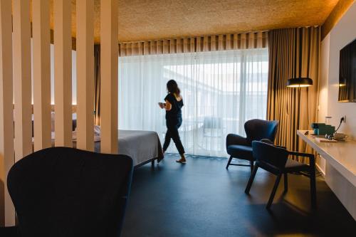 a woman walking in a hotel room with a bed at Canadiano Urban Nature Hotel in Ponta Delgada