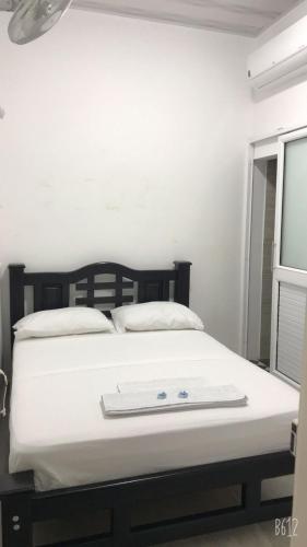 a white bed with a black headboard and a window at HOTEL POSADA DON JOSE in Aguachica