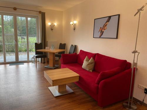a living room with a red couch and a table at Hotel TraumzeitHof in Eschede