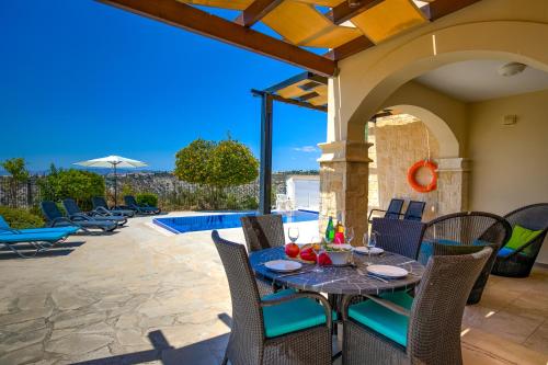 a patio with a table and chairs and a pool at 3 bedroom Villa Melandra with private pool and sea views, Aphrodite Hills Resort in Kouklia