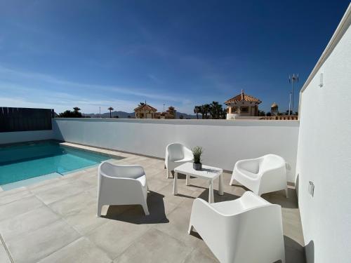 un patio con sillas blancas y una piscina en Villa Demi-Adore, en Mazarrón
