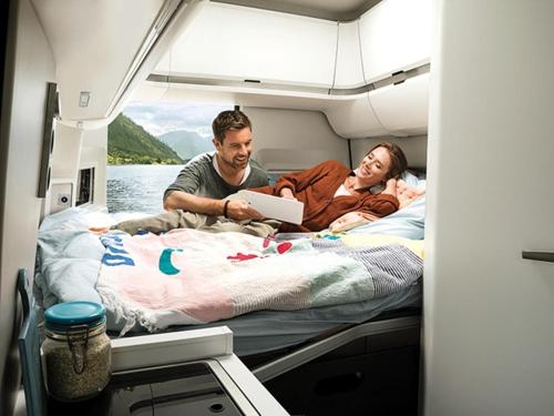 mężczyzna i kobieta leżący na łóżku z tabletem w obiekcie Campervan Rental Dublin - VW Grand California w Dublinie