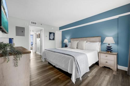 a bedroom with a large bed with a blue wall at Direct OCEANFRONT- King Bedroom- AMAZING VIEWS/Pools/Hot Tubs/Beach Access/Golf in Myrtle Beach