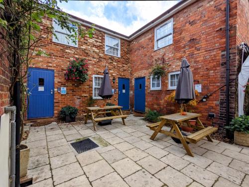 eine Terrasse mit Tischen und Sonnenschirmen vor einem Backsteingebäude in der Unterkunft The White Horse in Linslade