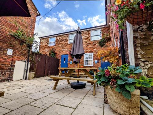 an umbrella sitting on a picnic table in front of a brick building at The White Horse in Linslade