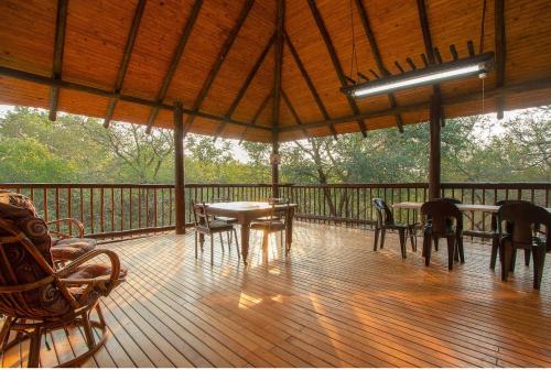 a porch with tables and chairs on a wooden deck at Kruger Wild Dog Inn in Marloth Park