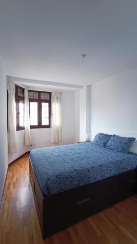een slaapkamer met een groot bed en een blauwe deken bij La Guarida del Pescador in Lastres
