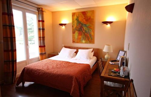 Schlafzimmer mit einem Bett, einem Schreibtisch und einem Fenster in der Unterkunft Hôtel Le Boïate in Arès