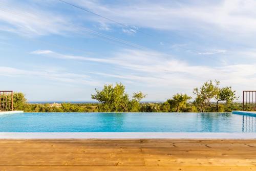 einen Pool mit blauem Wasser und Bäumen in der Unterkunft Quinta da Baleeira in Tavira