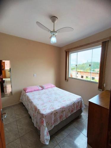 una camera da letto con un letto con cuscini rosa e una finestra di hospedagem recanto do sábia 4 a Caparaó Velho