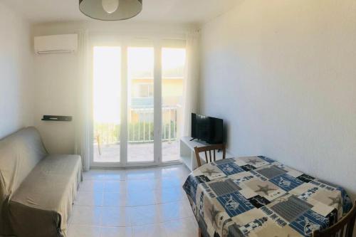 une chambre avec un lit, une télévision et une fenêtre dans l'établissement Situation idéale F2, 2 eme ligne,climatisé, plage, à Palavas-les-Flots