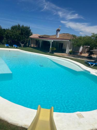 a large blue swimming pool with a yellow object in front of a house at Chalet Brisas del Mar in Chiclana de la Frontera
