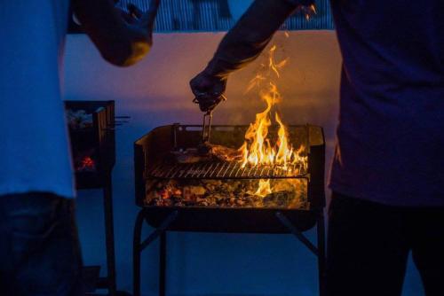 una persona está cocinando comida en una parrilla en Long Beach Surf House en Corralejo