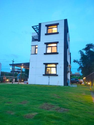 a white building with windows on top of a green field at 遇見山嵐獨棟包棟民宿寵物友善 in Yuanshan