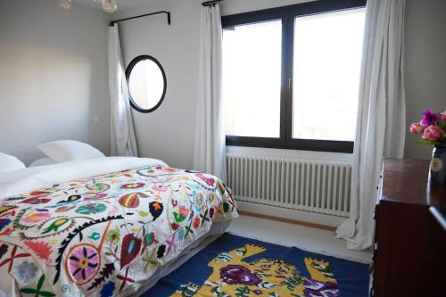 a bedroom with a bed with a colorful blanket and a window at Loft l'Écluse 2, parking gratuit in Saint-Valery-sur-Somme