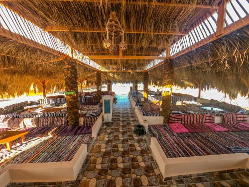 an outdoor restaurant with chairs and a straw roof at Flight Mode Camp in Nuweiba