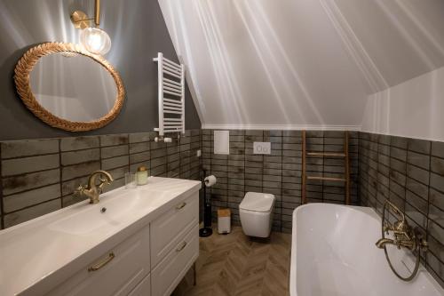 uma casa de banho com um lavatório, uma banheira e um espelho. em Narnia Apartment em Toruń