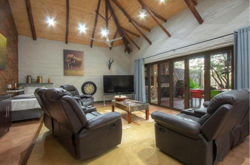 a living room with two chairs and a television at Kruger Wild Dog Inn in Marloth Park