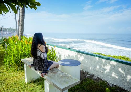 a woman sitting on a bench looking at the ocean at Solaris Varkala Beach Resort By VOYE HOMES in Varkala