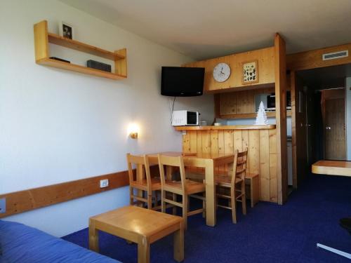 Cette chambre comprend une cuisine, une table et des chaises. dans l'établissement Studio skis aux pieds, proche commerces, balcon, 5 personnes, animaux acceptés, Arc 1800 - FR-1-411-782, à Bourg-Saint-Maurice