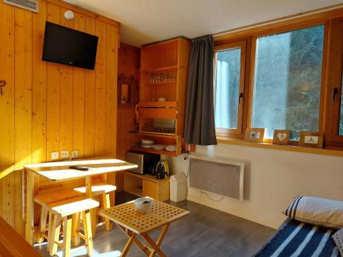 - un salon avec des murs en bois, une table et une télévision dans l'établissement Studio cosy pour 2, au pied des pistes, Wi-Fi inclus, proche commerces et ESF à Arc 1800 - FR-1-411-811, à Bourg-Saint-Maurice