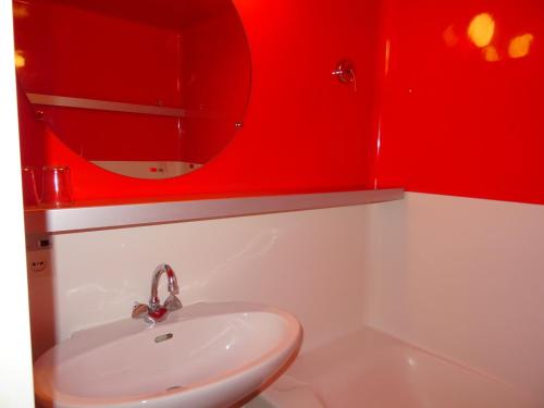 La salle de bains rouge est pourvue d'un lavabo et d'un miroir. dans l'établissement Studio skis aux pieds, proche commerces, balcon, 5 personnes, animaux acceptés, Arc 1800 - FR-1-411-782, à Bourg-Saint-Maurice