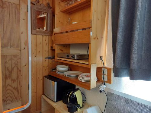 une cuisine avec un micro-ondes et de la vaisselle dans une pièce dans l'établissement Studio cosy pour 2, au pied des pistes, Wi-Fi inclus, proche commerces et ESF à Arc 1800 - FR-1-411-811, à Bourg-Saint-Maurice