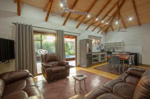 a living room with a couch and a table and a kitchen at Kruger Wild Dog Inn in Marloth Park