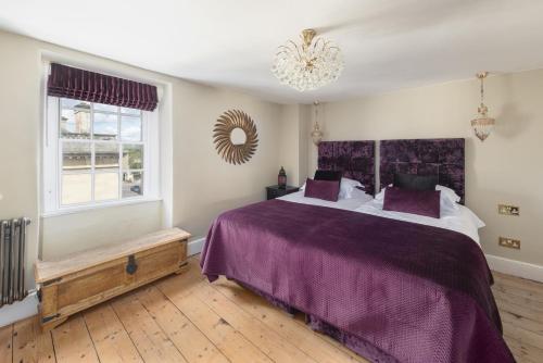 um quarto com uma cama com lençóis roxos e uma janela em Darcys' Pride em Bath