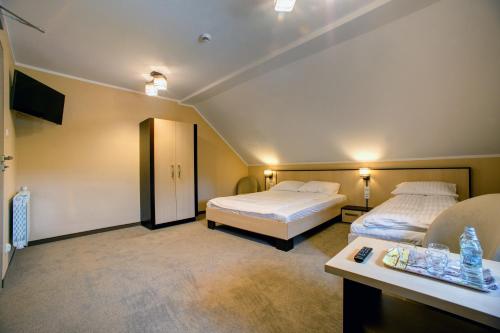 a hotel room with two beds and a table at Zajazd Sanocki in Sanok