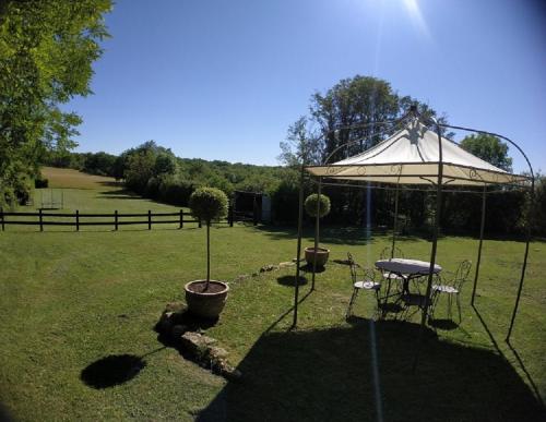 a table and chairs under an umbrella in a field at Maison Les Chandelles in Loupiac