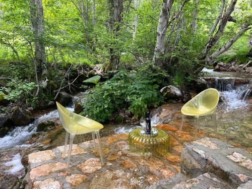 two chairs sitting on a rock by a stream at Vikendica GORSKI VUK Jelovica in Berane