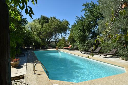 una piscina con panchine e alberi in un cortile di La Mandarine a Piolenc