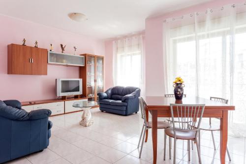 sala de estar con mesa, sillas y TV en casa Simona en Catania