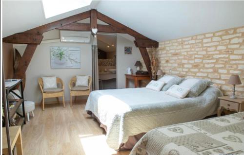 a bedroom with two beds and a brick wall at Le Moulin de Mayence in Plazac