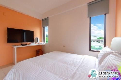a bedroom with a white bed and a flat screen tv at 遇見山嵐獨棟包棟民宿寵物友善 in Yuanshan