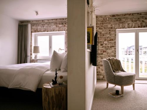a bedroom with a bed and a chair and windows at 1884 Norderney in Norderney