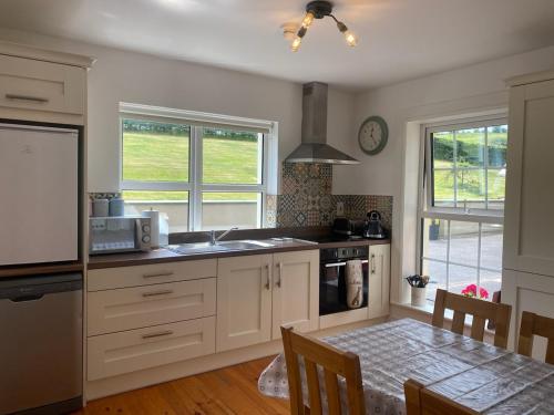 una cocina con armarios blancos y una mesa con comedor. en The Lodge Donegal Town, en Donegal