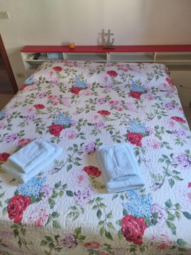 uma cama com toalhas com uma colcha floral em Monolocale in centro storico a grado em Grado
