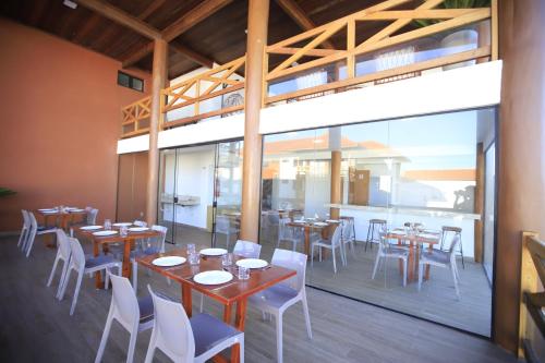 een restaurant met houten tafels en witte stoelen bij UNNAVENTURA VILA ATLÂNTIDA in Luis Correia