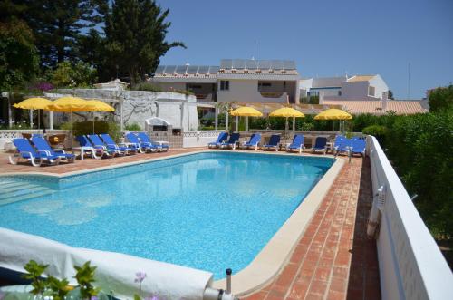 a swimming pool with blue chairs and umbrellas at 2 Bed Flat - Sleeps 4 - Pool - Terrace - Parking in Luz