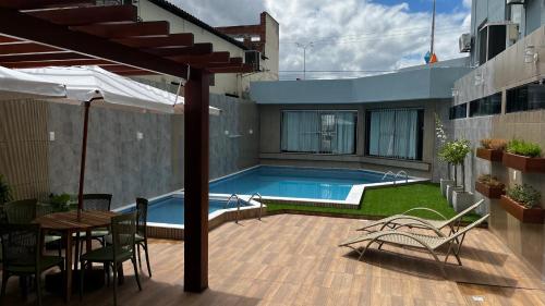 a swimming pool with a table and chairs and an umbrella at Hotel Sabino Palace in Mossoró