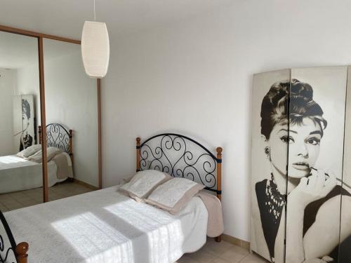 Schlafzimmer mit einem Bett mit Bild einer Frau in der Unterkunft Maison Toulouges Climatisée - Proche Perpignan in Toulouges